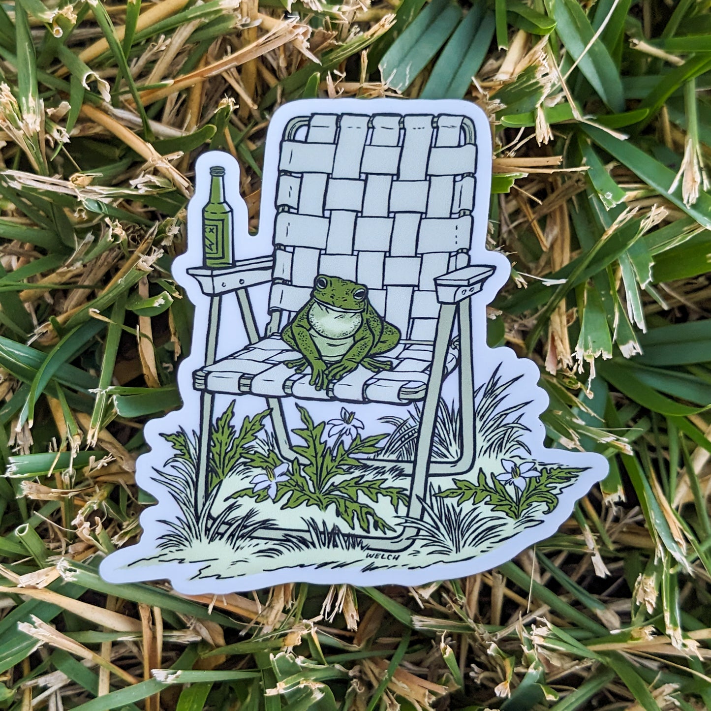 A sticker with an illustration of a frog sitting in a vinyl folding chair. He has a bottle of beer.