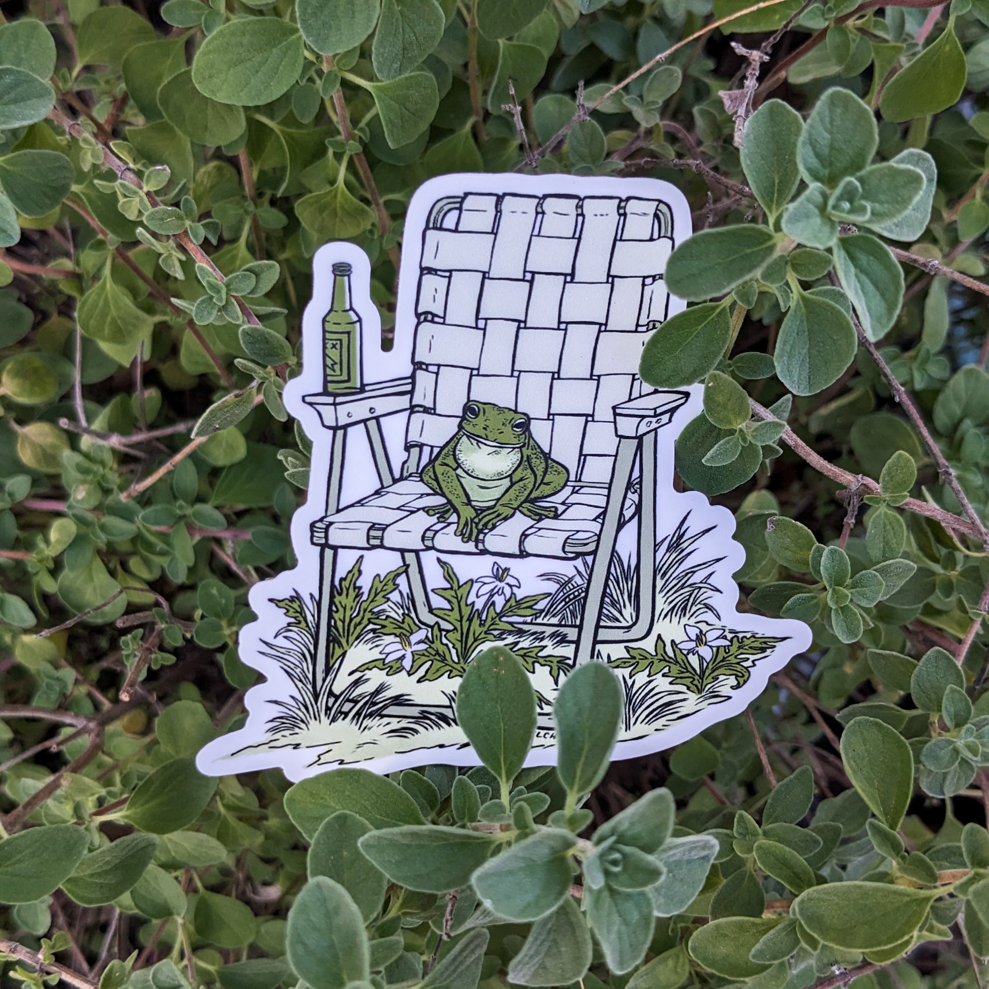 A sticker with an illustration of a frog sitting in a vinyl folding chair. He has a bottle of beer.