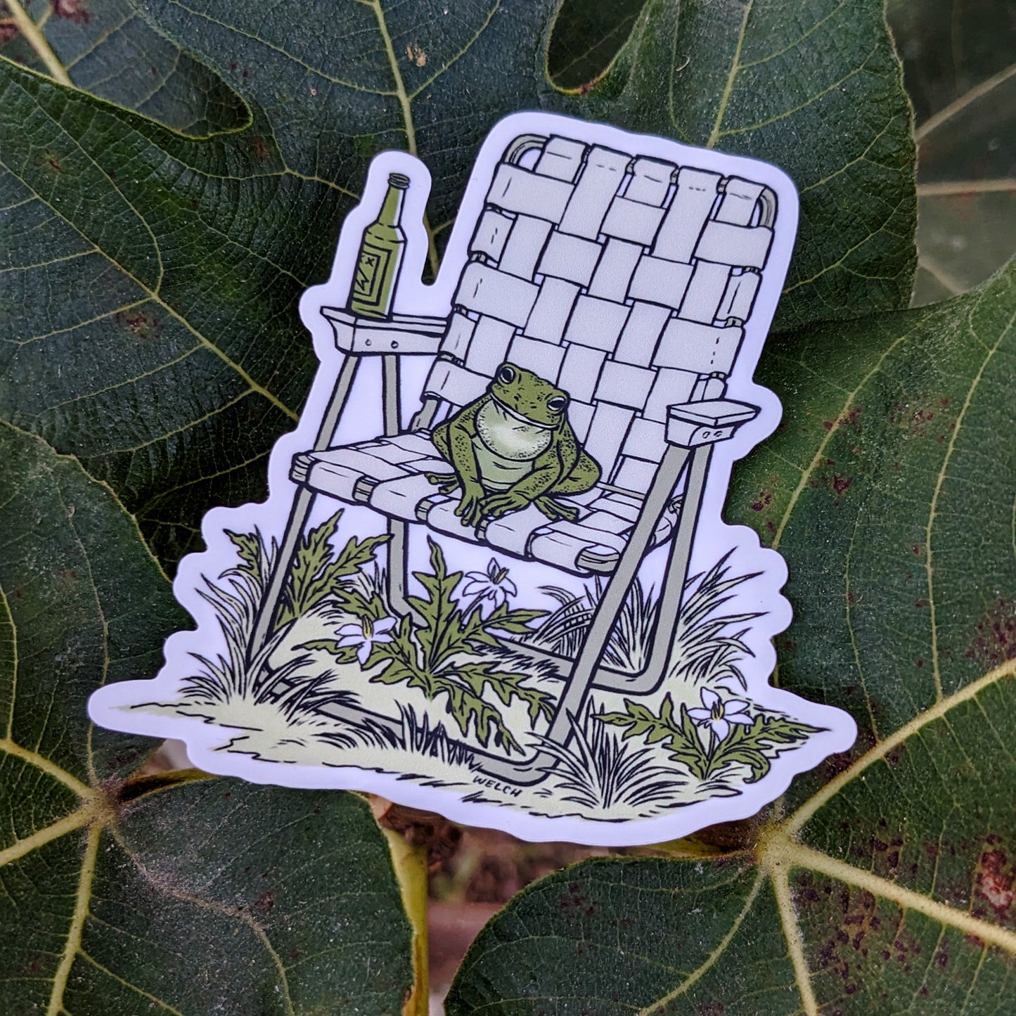 A sticker with an illustration of a frog sitting in a vinyl folding chair. He has a bottle of beer.